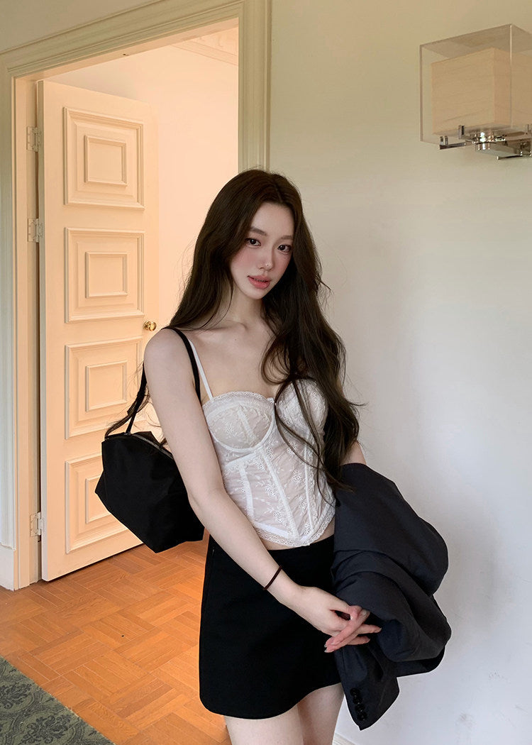 Model wearing an ivory embroidered corset camisole under a dark blazer