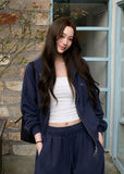 Model wearing a navy embroidered zip-up hoodie and drawstring sweatpants set