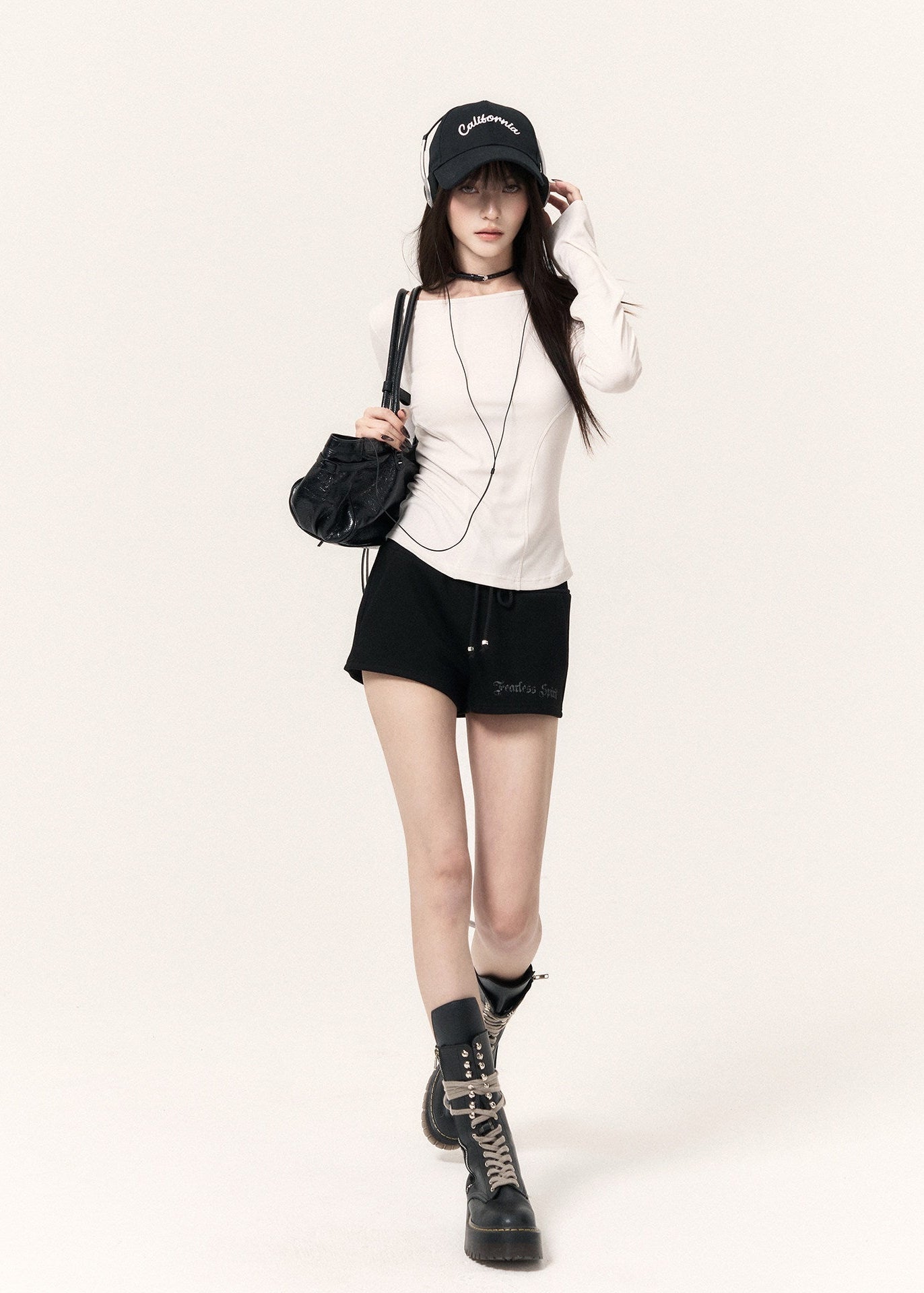 White long-sleeve top with an angel wing back print styled with a black mini skirt and cap