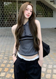 Model wearing a blue-gray sleeveless polo knit top with dark horizontal chest stripes