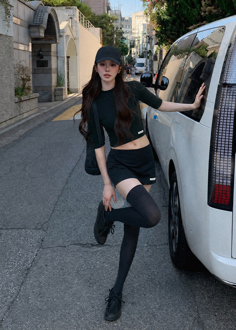 Model wearing a black half-turtleneck knit top and A-line mini skirt set