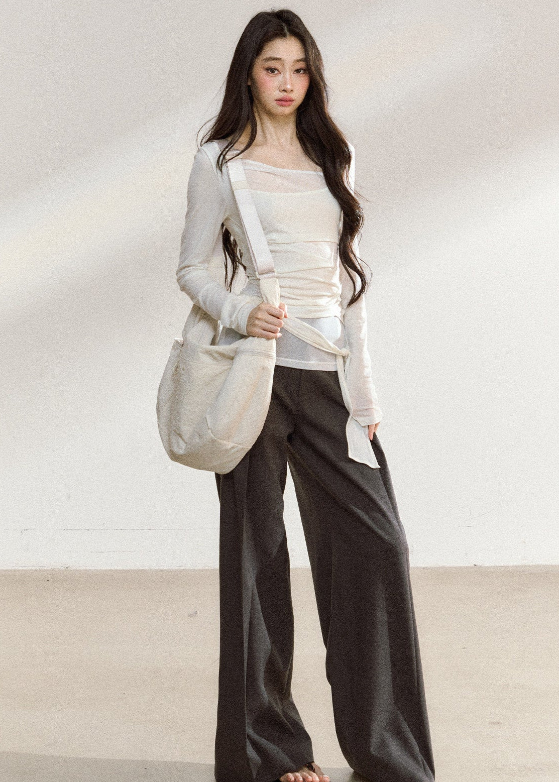 White asymmetric layered long-sleeve top with sheer panels and draped waist ties