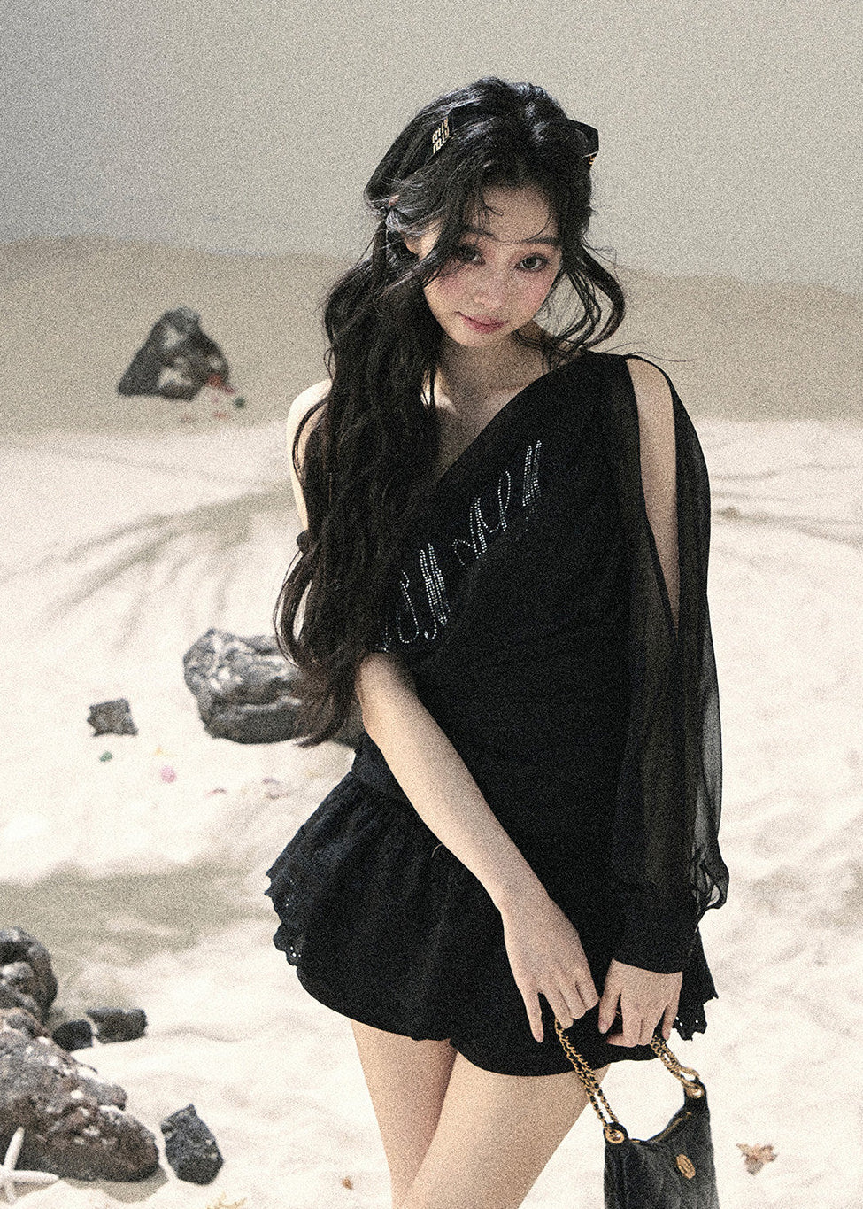 Woman wearing black asymmetric off-shoulder ruched top with mesh detailing