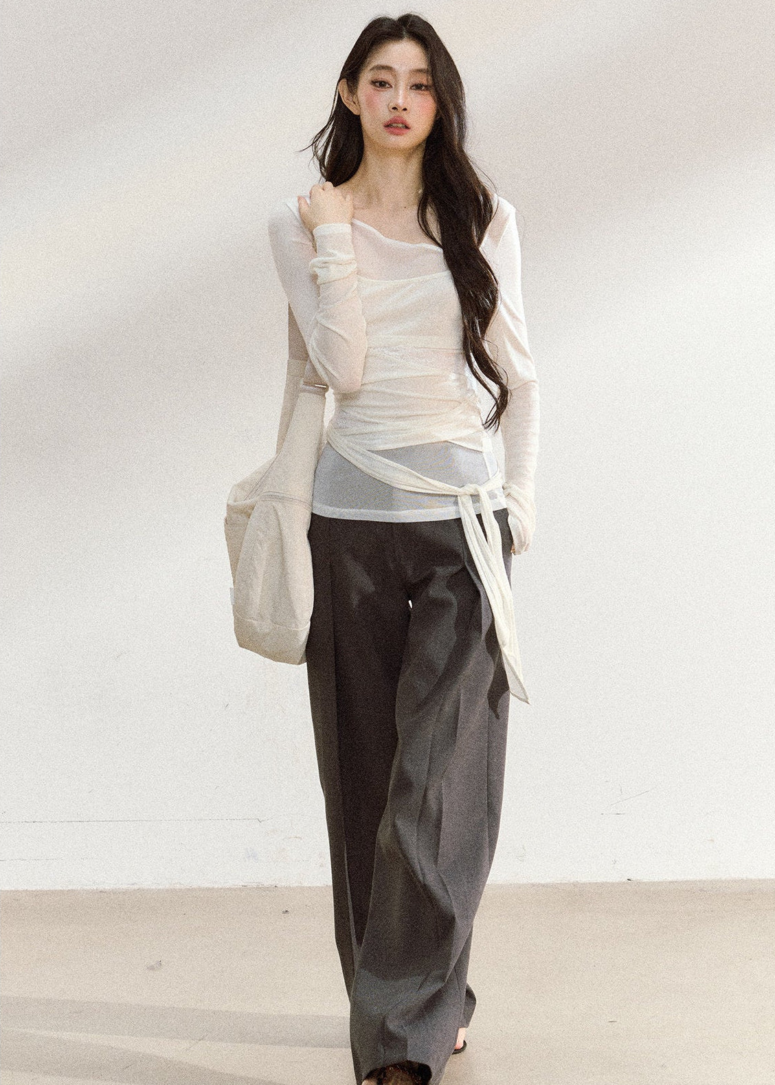 White asymmetric layered long-sleeve top with sheer panels and draped waist ties