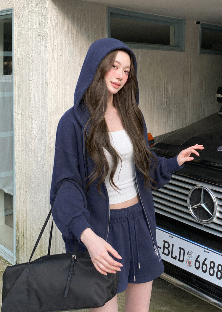 Model wearing a navy embroidered zip-up hoodie and drawstring sweatpants set