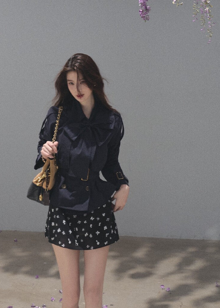 Black bow-neck jacket paired with a khaki belted midi skirt