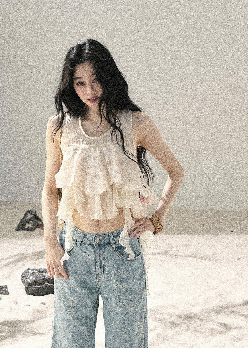 Woman wearing ivory tiered ruffle sleeveless top with light blue denim jeans