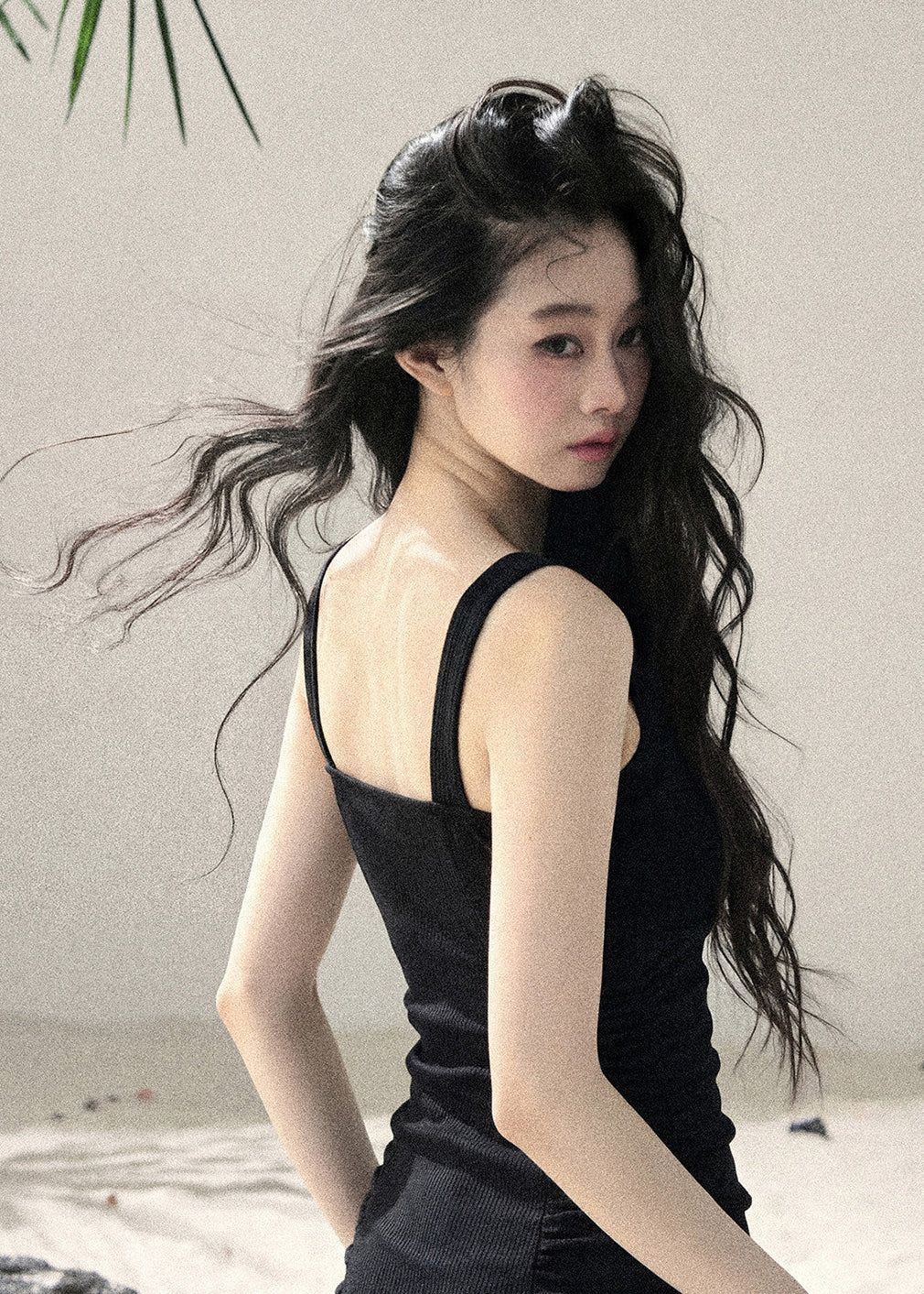 Woman wearing black halter cutout knit mini dress layered with white cardigan