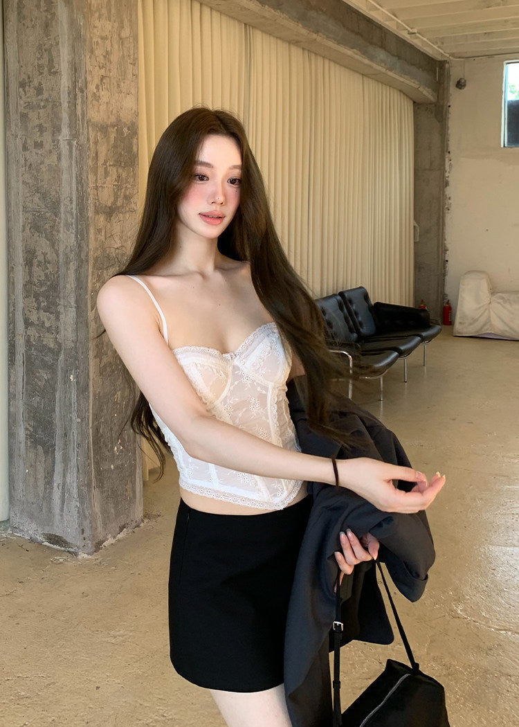 Model wearing an ivory embroidered corset camisole under a dark blazer