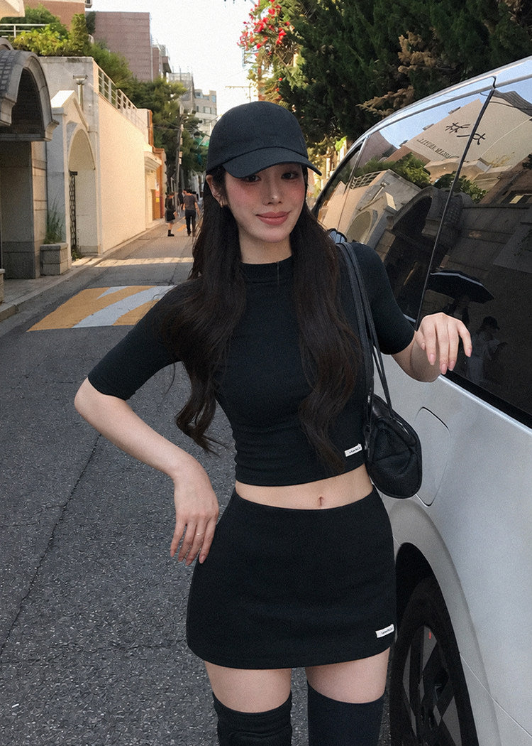 Model wearing a black half-turtleneck knit top and A-line mini skirt set
