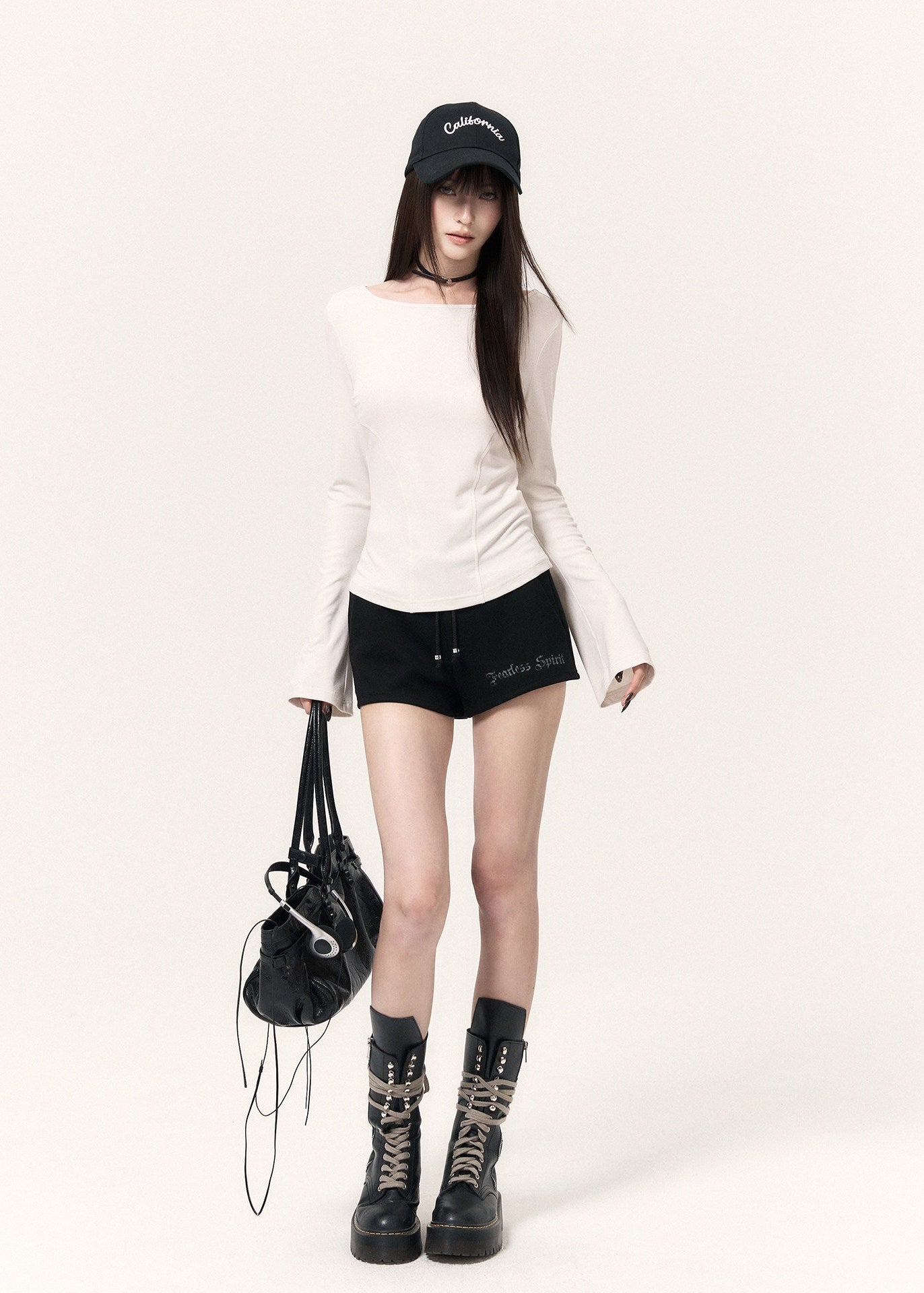 White long-sleeve top with an angel wing back print styled with a black mini skirt and cap
