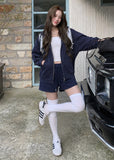 Model wearing a navy embroidered zip-up hoodie and drawstring sweatpants set