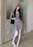 Model wearing a gray faux-layered hooded top and pleated mini skirt set
