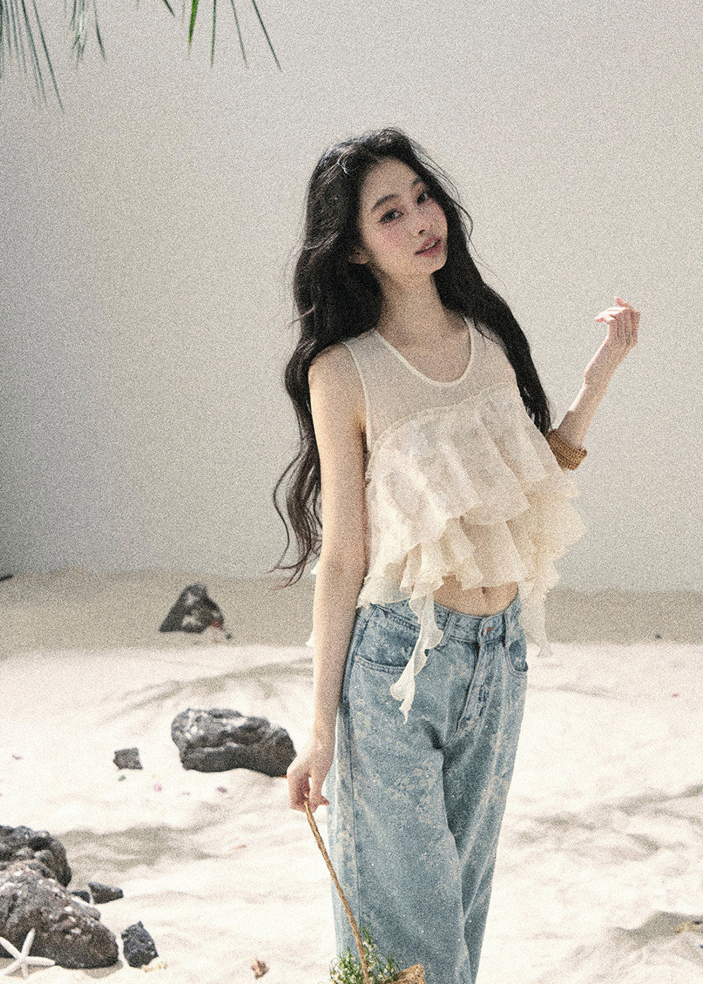 Woman wearing ivory tiered ruffle sleeveless top with light blue denim jeans