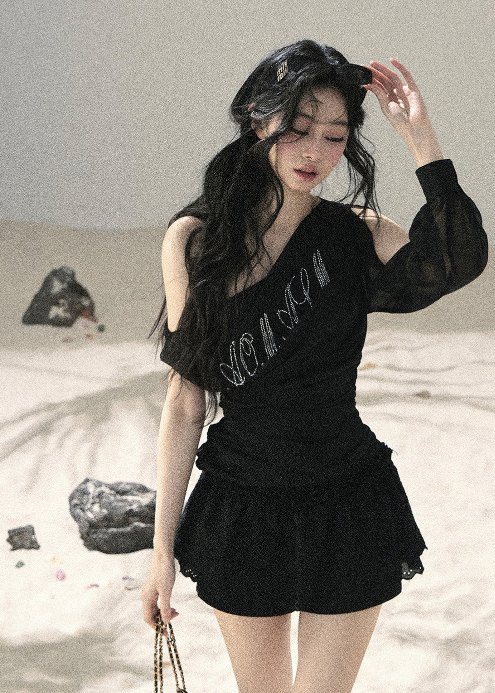 Woman wearing black asymmetric off-shoulder ruched top with mesh detailing