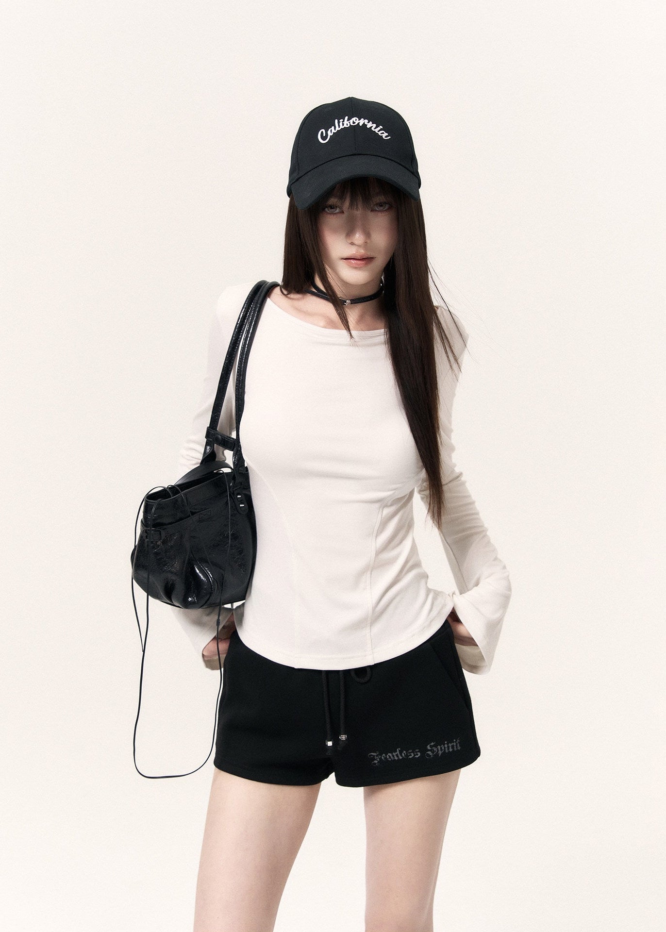 White long-sleeve top with an angel wing back print styled with a black mini skirt and cap