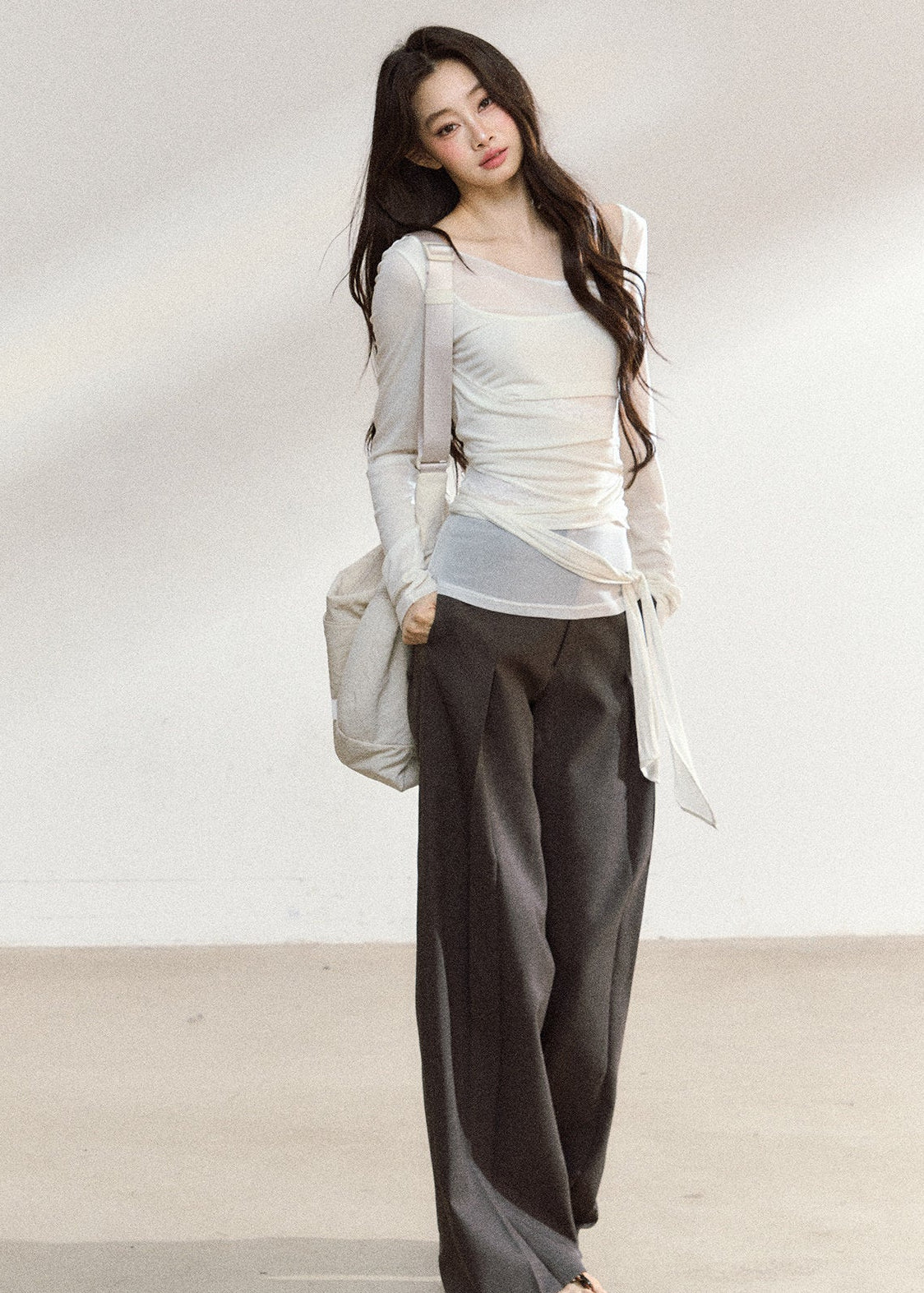 White asymmetric layered long-sleeve top with sheer panels and draped waist ties