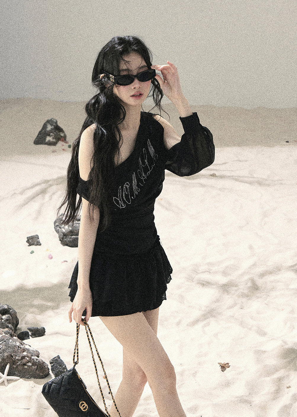 Woman wearing black asymmetric off-shoulder ruched top with mesh detailing