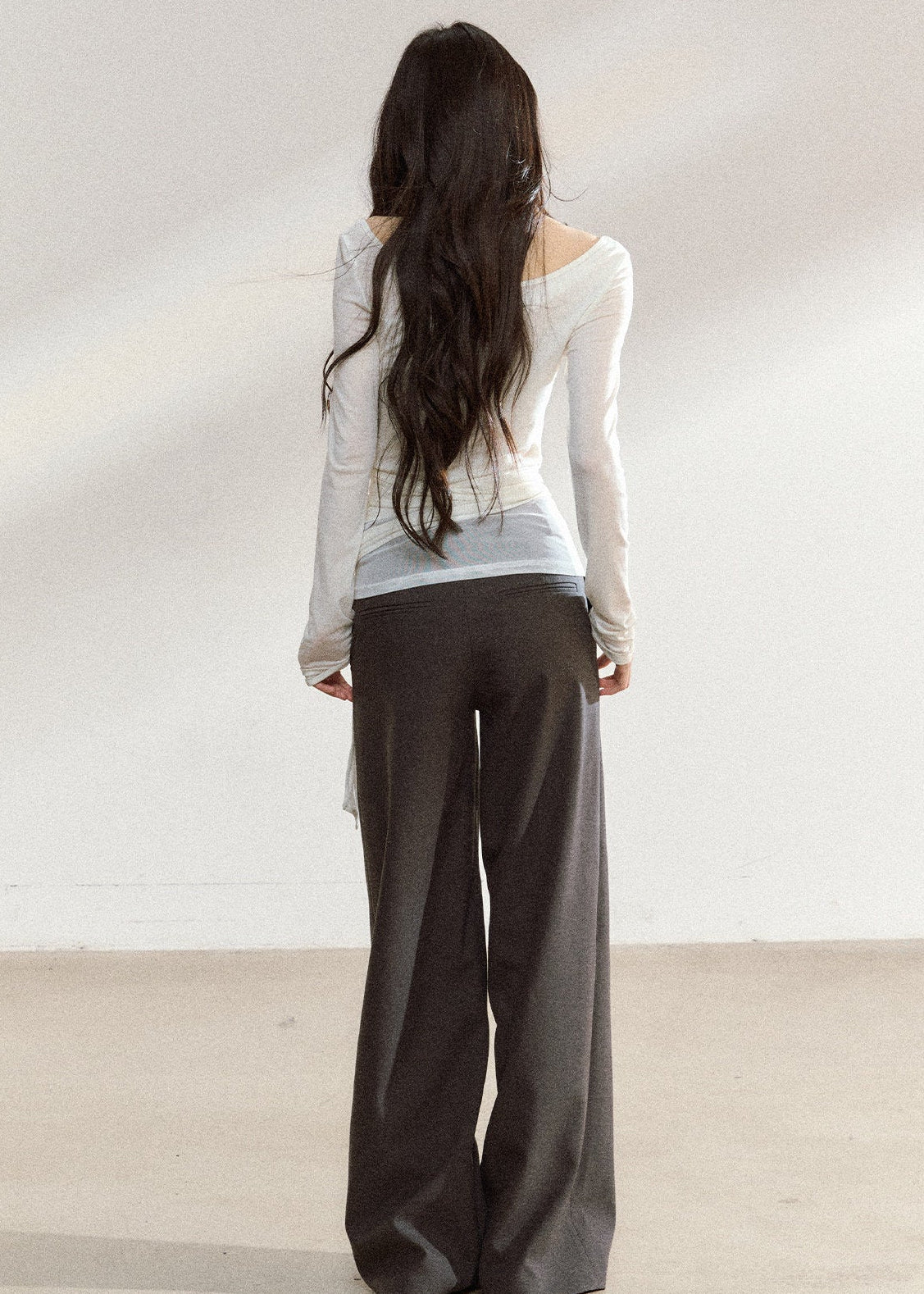 White asymmetric layered long-sleeve top with sheer panels and draped waist ties