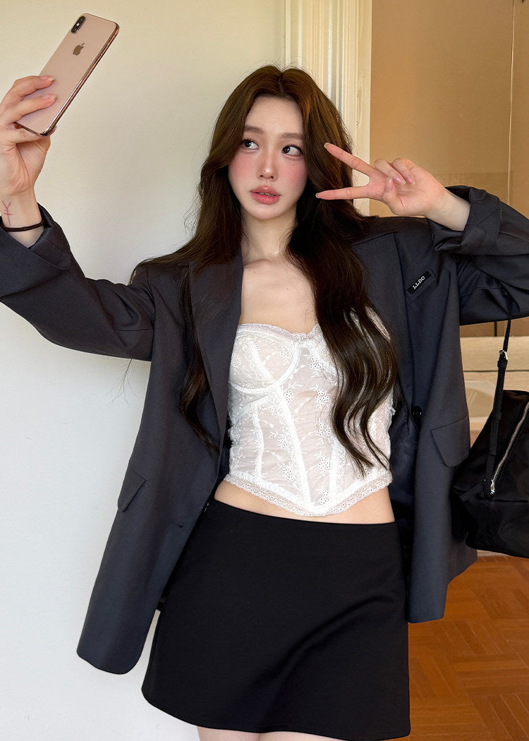 Model wearing an ivory embroidered corset camisole under a dark blazer