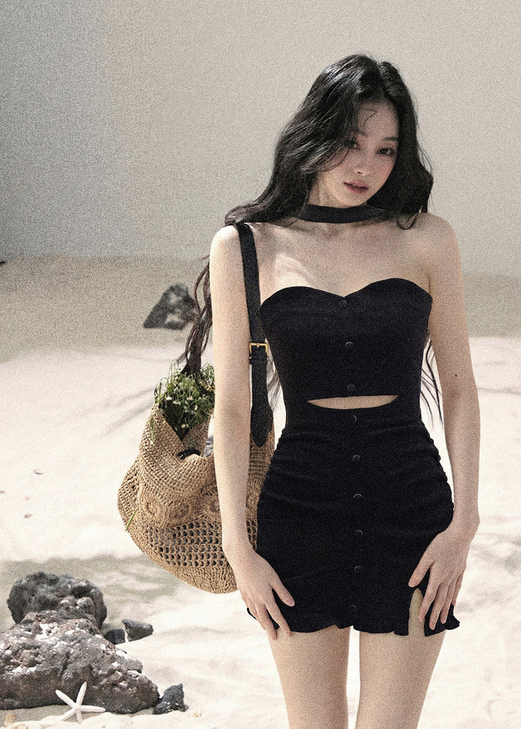 Woman wearing black halter cutout knit mini dress layered with white cardigan