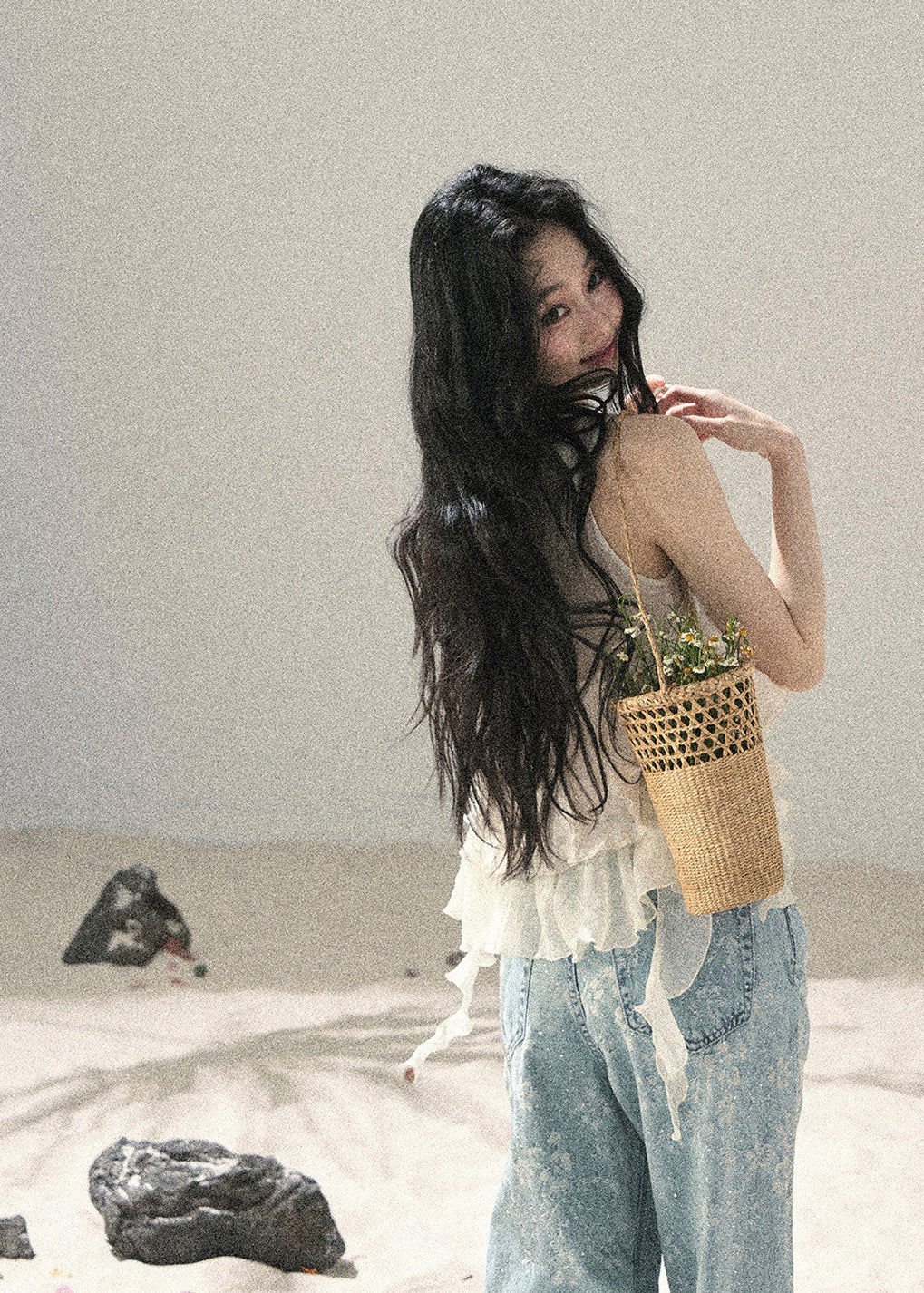 Woman wearing ivory tiered ruffle sleeveless top with light blue denim jeans