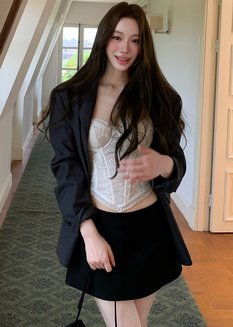 Model wearing an ivory embroidered corset camisole under a dark blazer