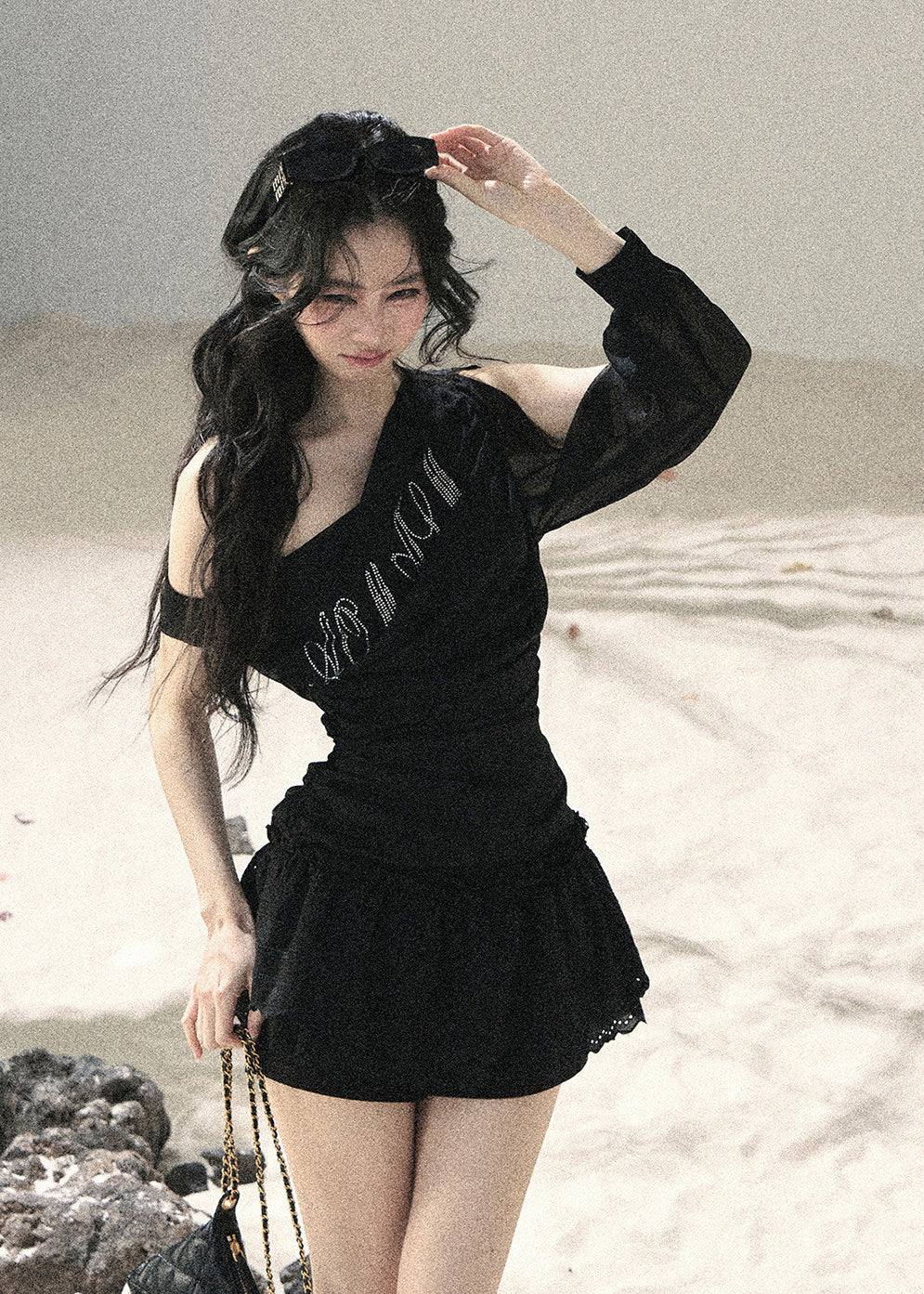 Woman wearing black asymmetric off-shoulder ruched top with mesh detailing