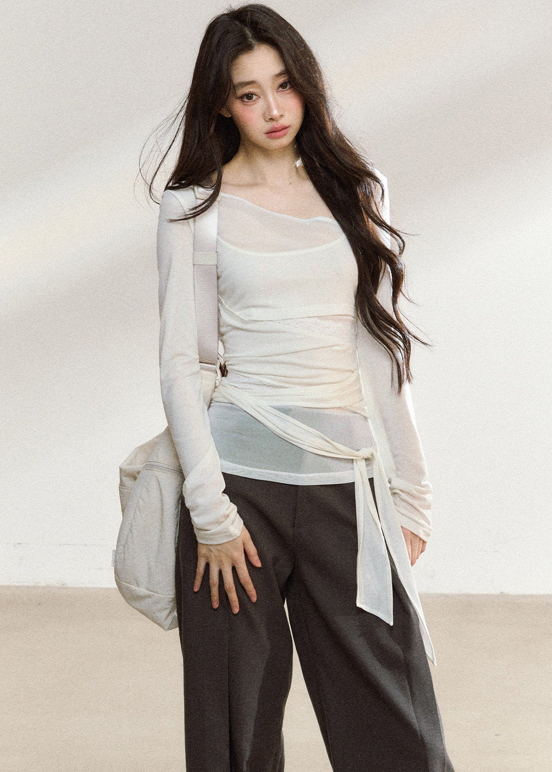 White asymmetric layered long-sleeve top with sheer panels and draped waist ties