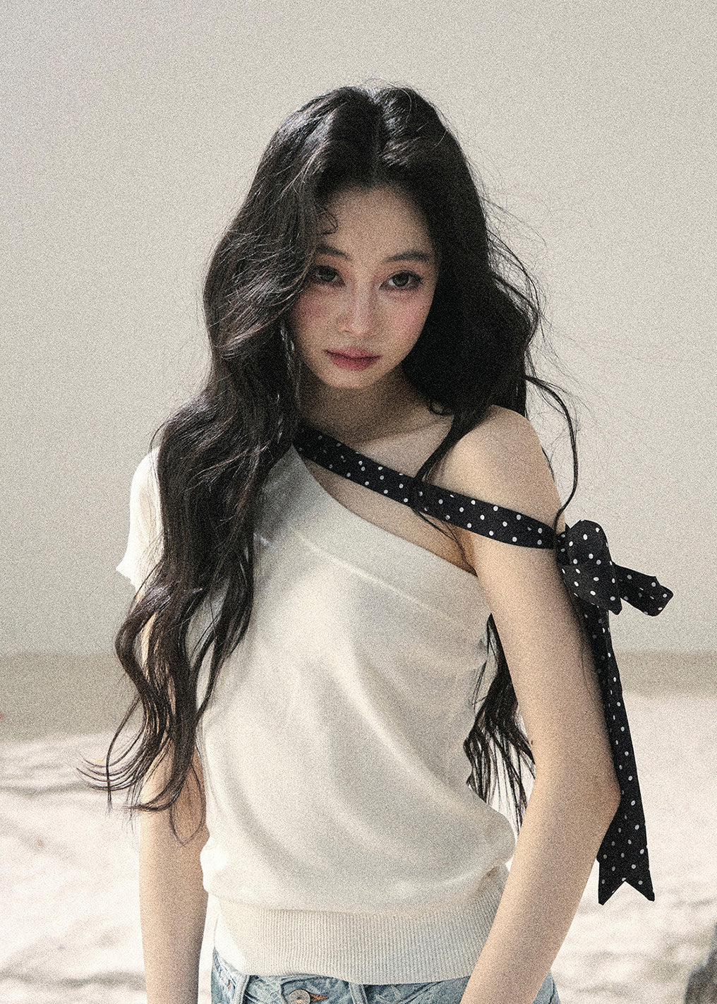 White one-shoulder knit top with black polka dot ribbon detail