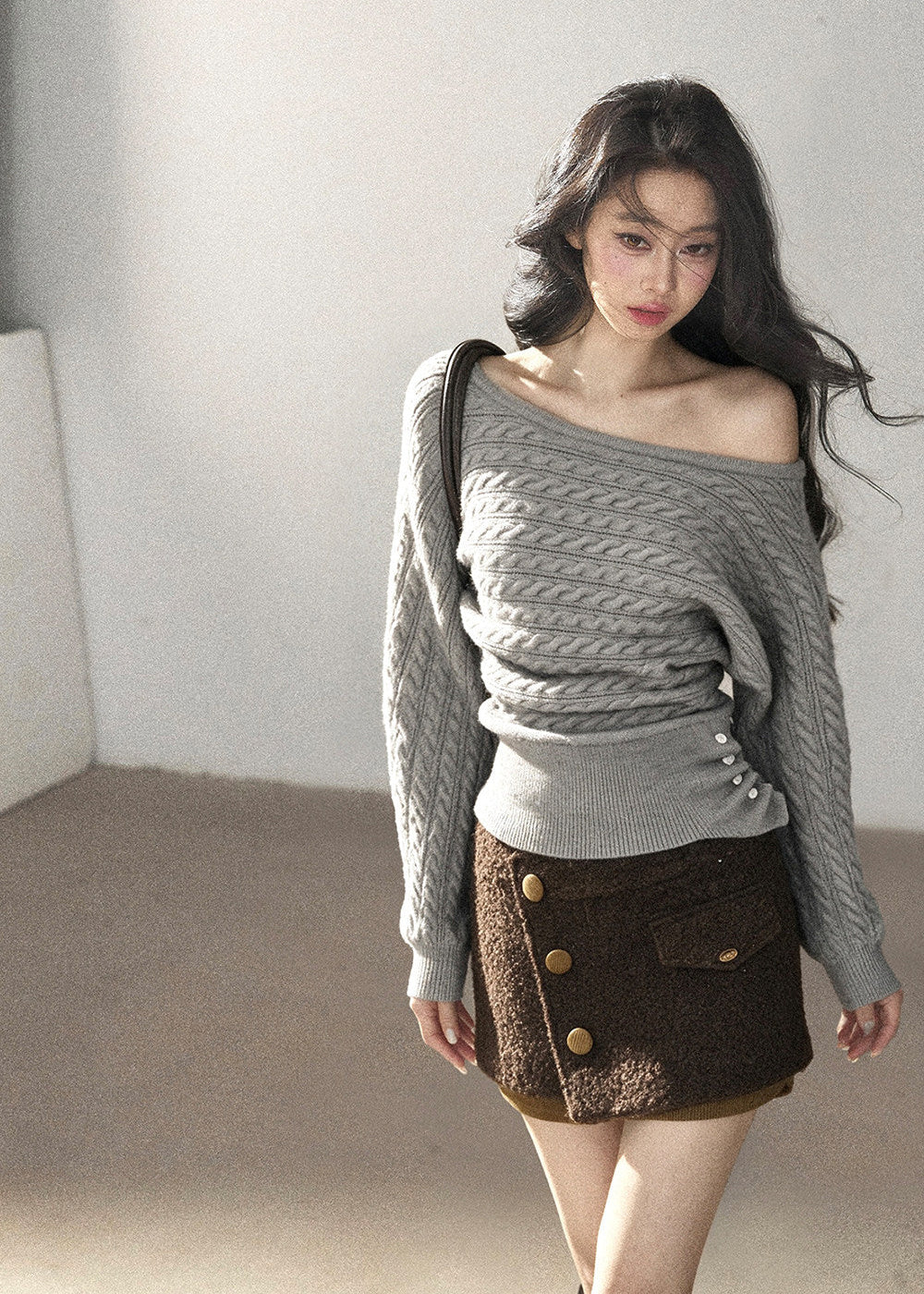 Grey one-shoulder cable knit sweater styled with a brown mini skirt