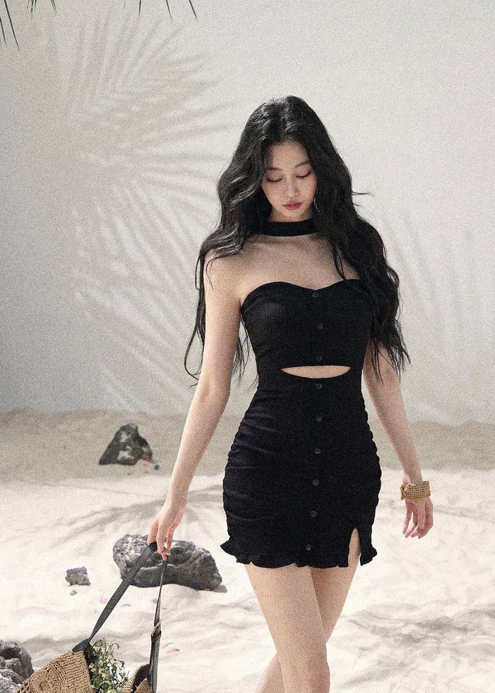 Woman wearing black halter cutout knit mini dress layered with white cardigan