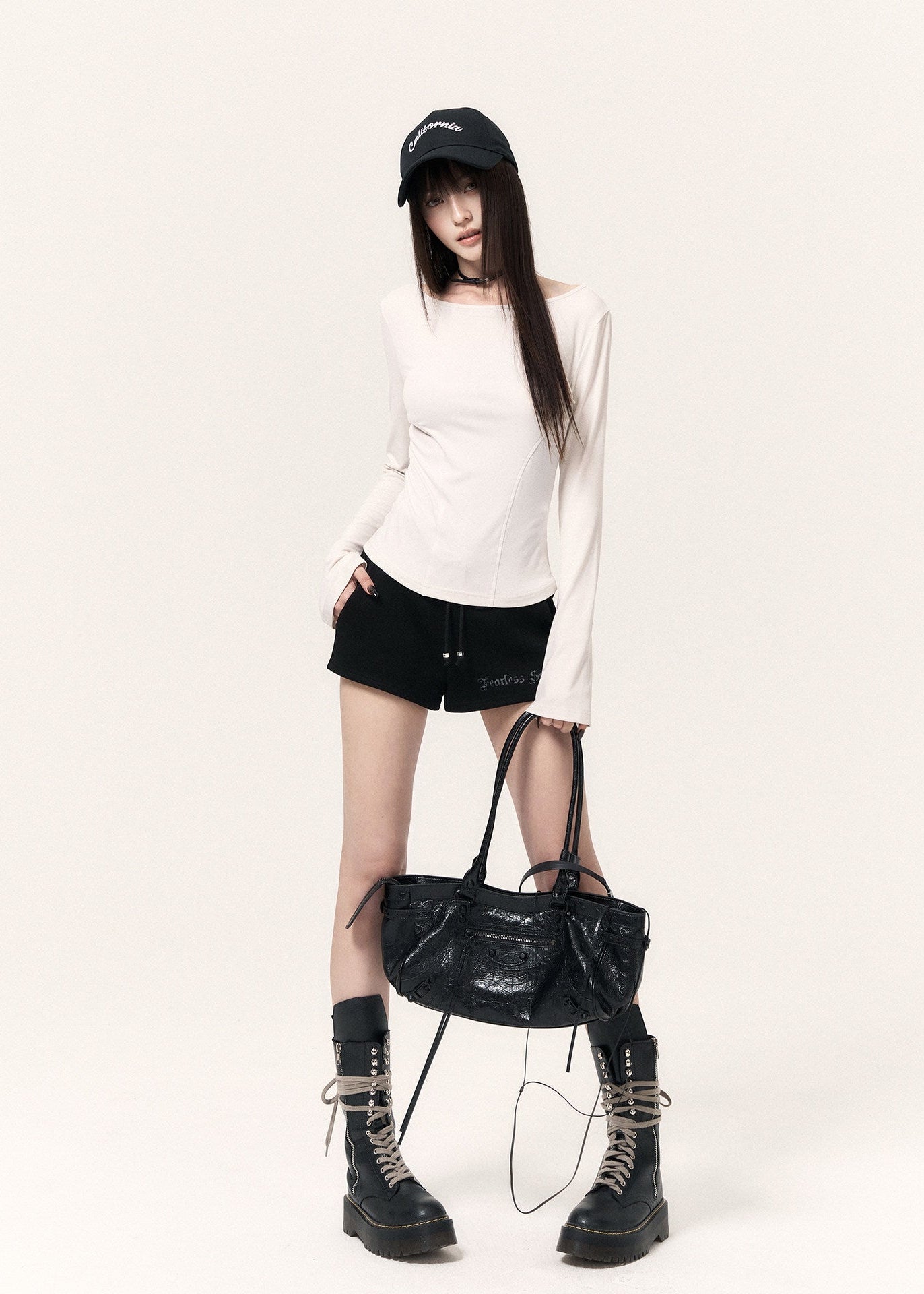 White long-sleeve top with an angel wing back print styled with a black mini skirt and cap