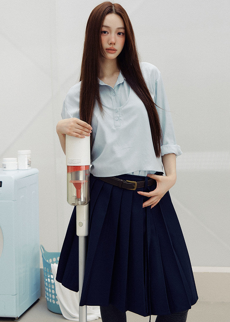 Navy pleated skirt with an asymmetric hem styled with knee-high socks and brown loafers