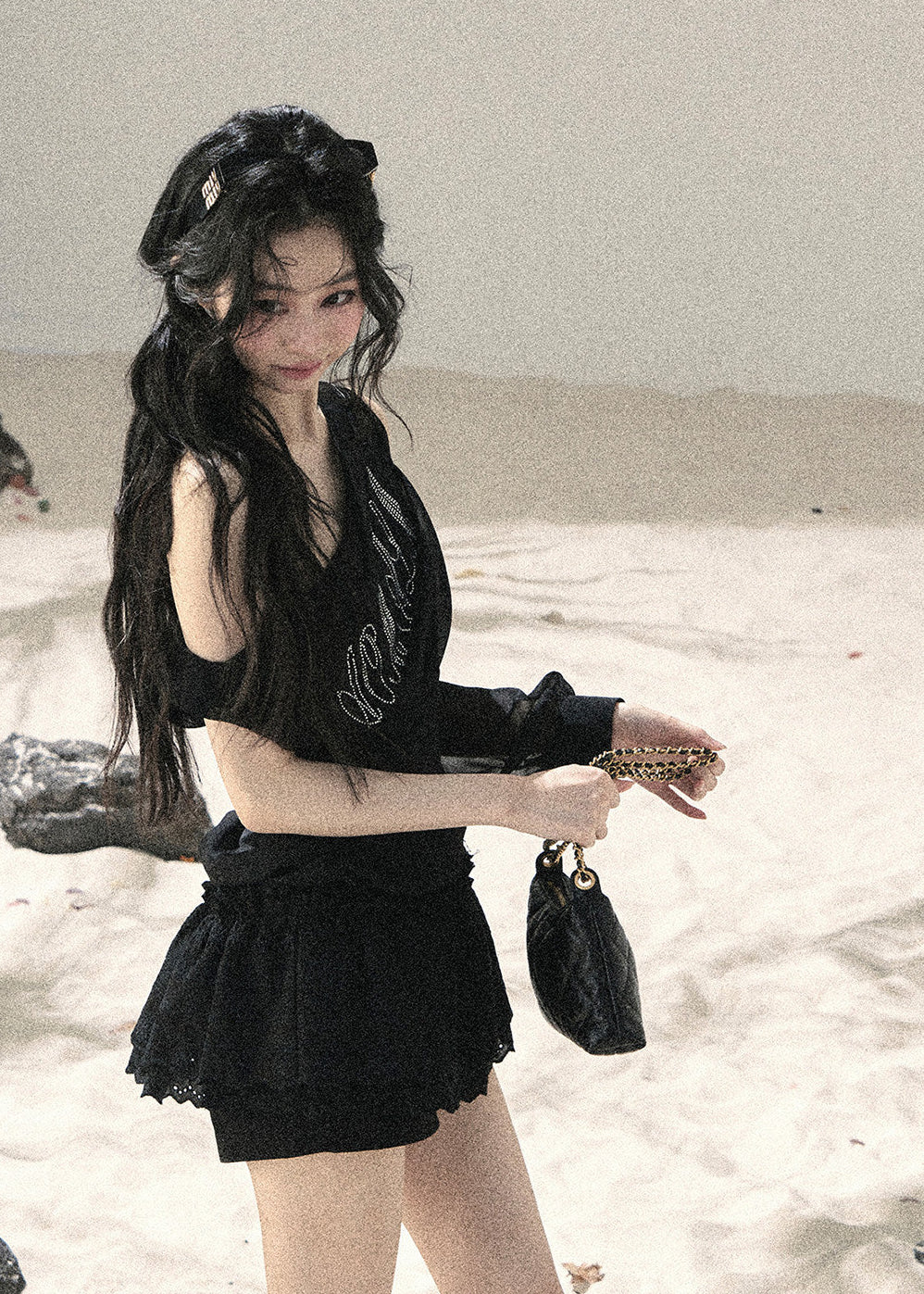 Woman wearing black asymmetric off-shoulder ruched top with mesh detailing
