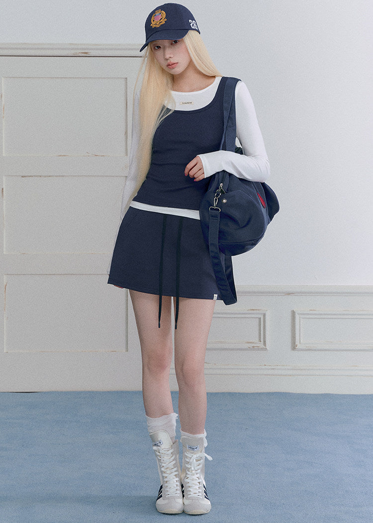 Model wearing a navy and white faux-layered top with a drawstring mini skirt