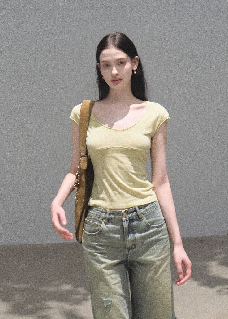 Model wearing distressed green wide-leg jeans with a cropped top