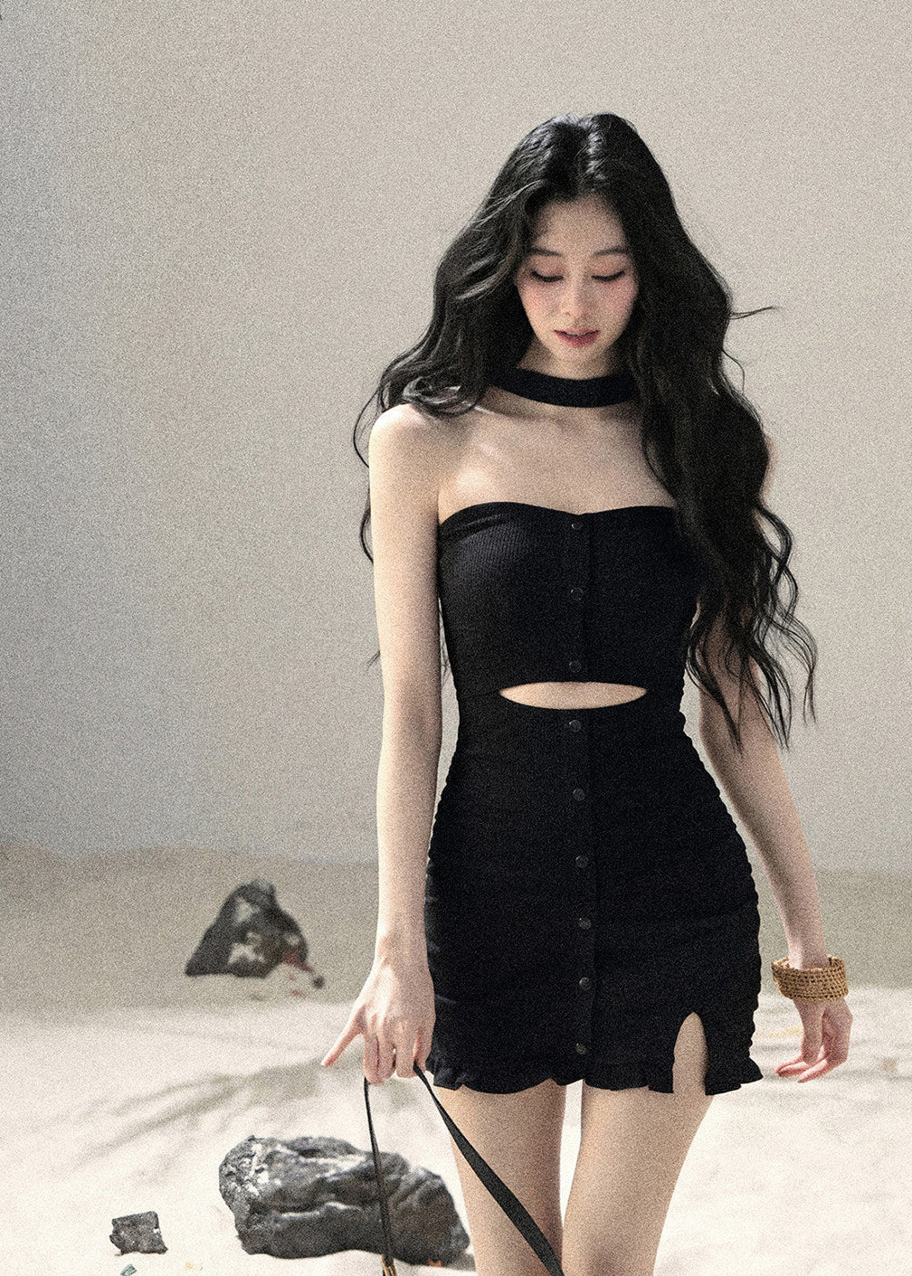 Woman wearing black halter cutout knit mini dress layered with white cardigan