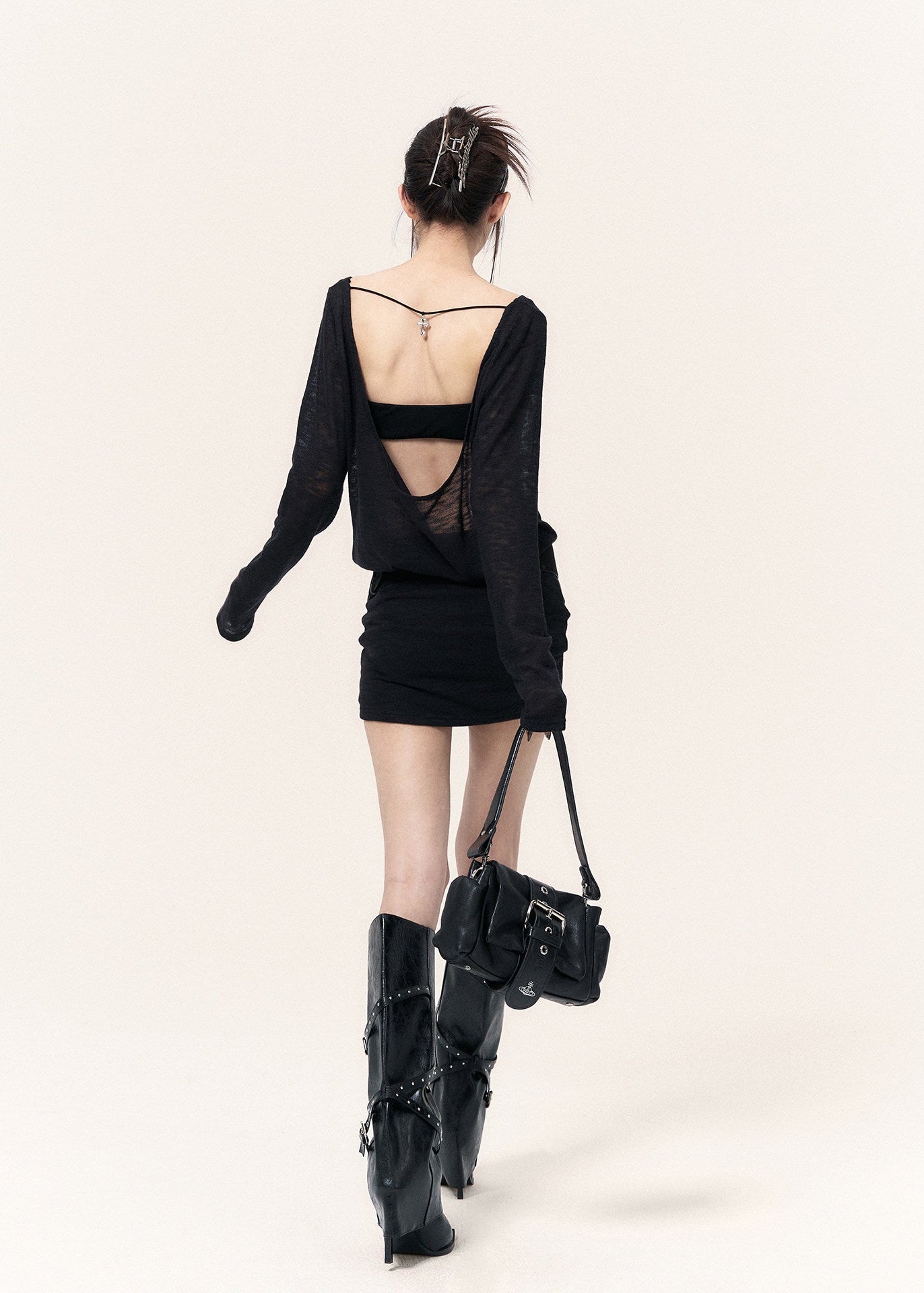 Back view of a black open-back dress with cross straps and a metal pendant