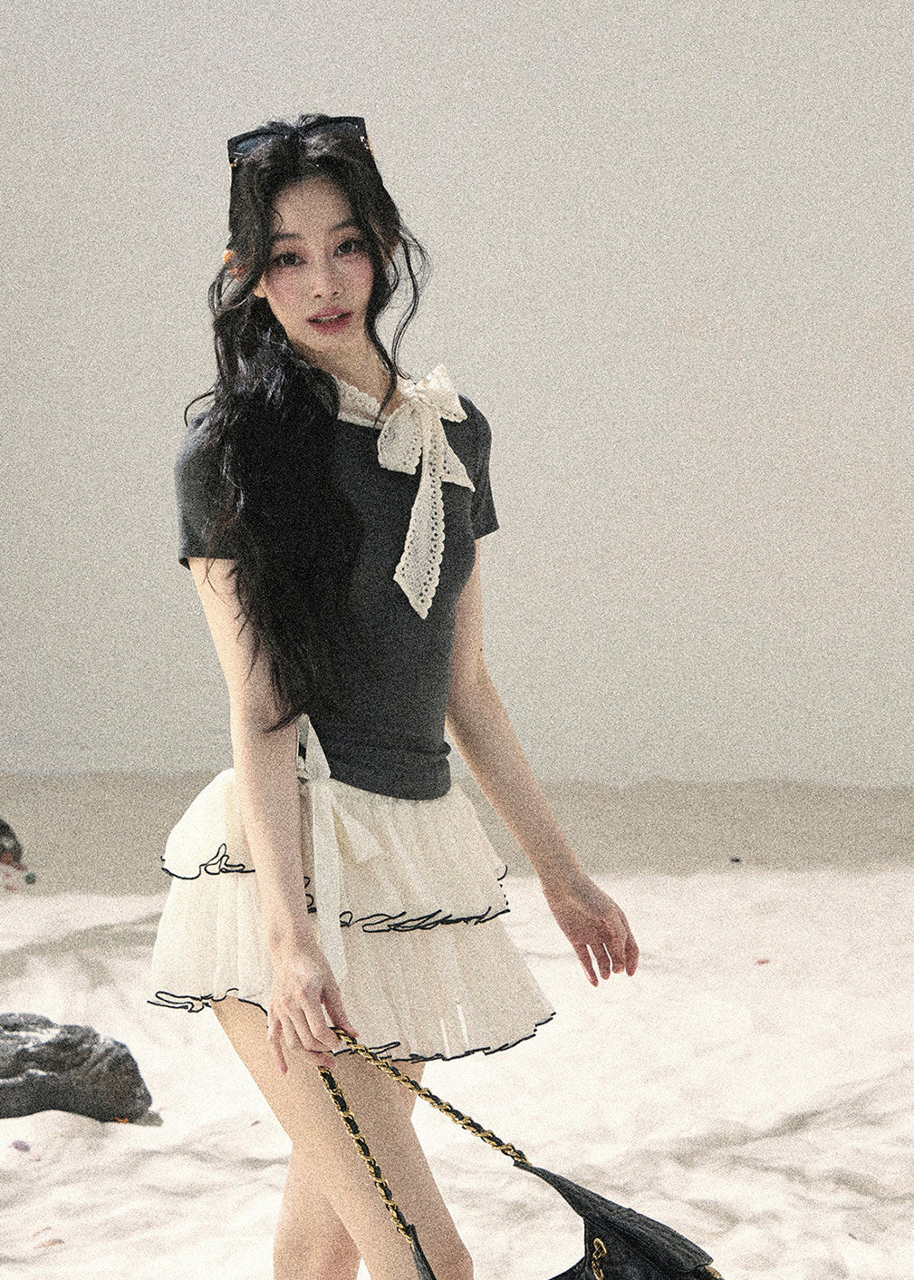 Woman wearing gray fitted T-shirt with contrast white lace ribbon bow