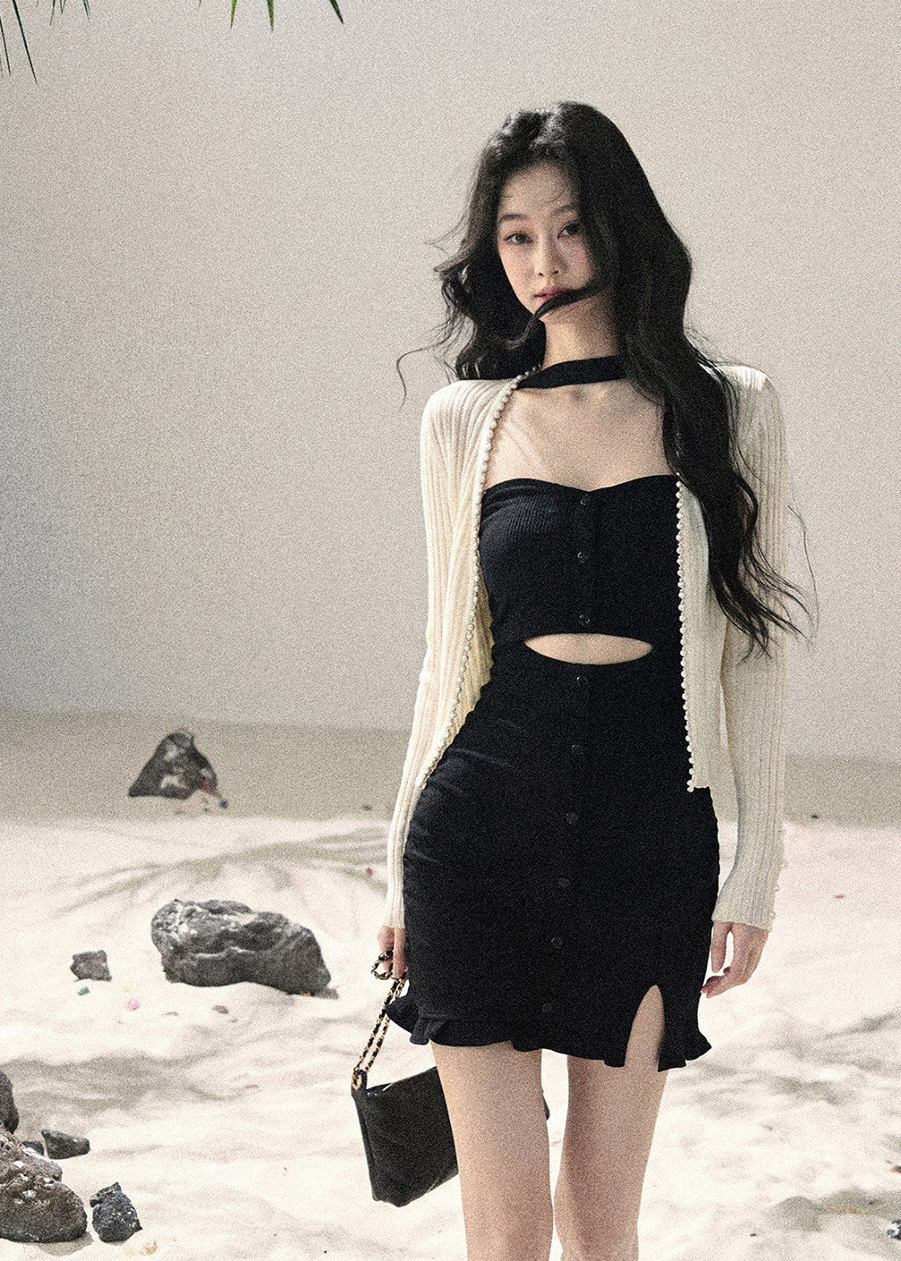 Woman wearing black halter cutout knit mini dress layered with white cardigan