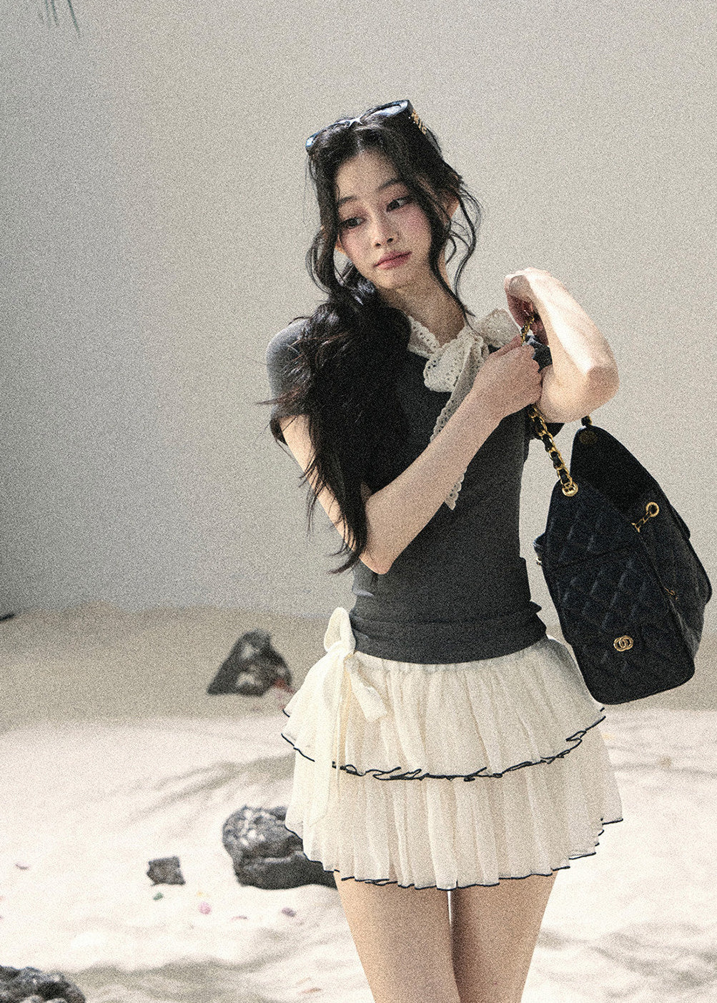 Woman wearing gray fitted T-shirt with contrast white lace ribbon bow