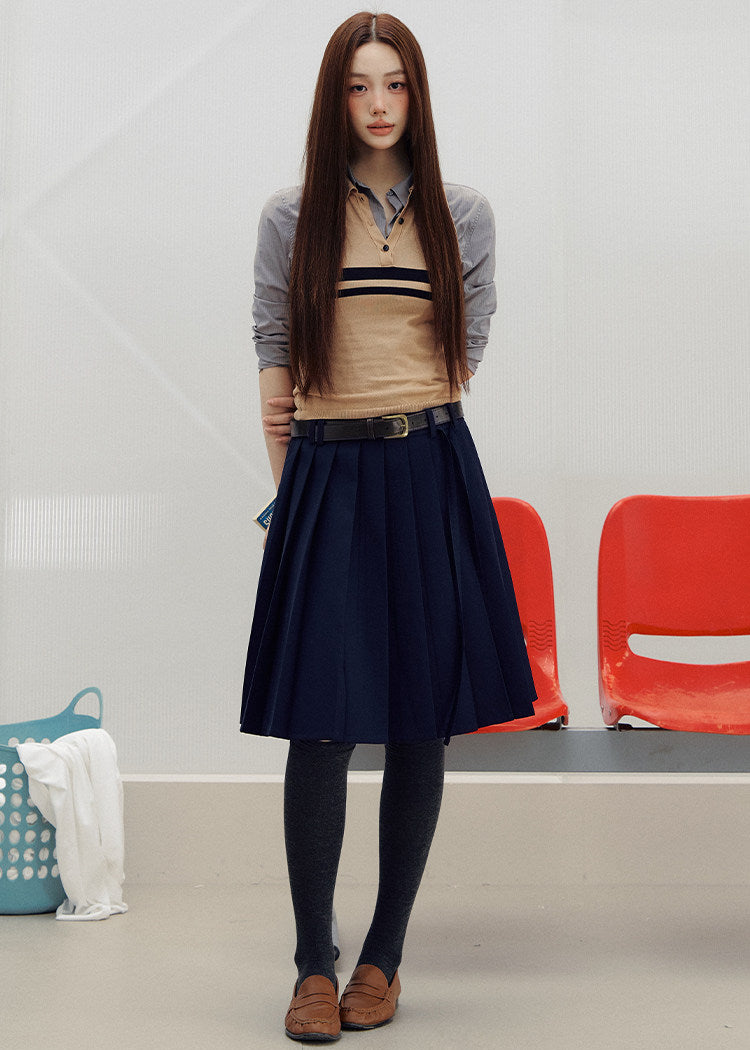 Navy pleated skirt with an asymmetric hem styled with knee-high socks and brown loafers