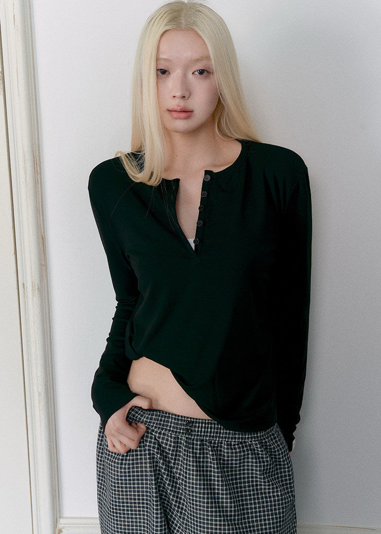Model wearing a black Tencel-wool Henley long-sleeve top
