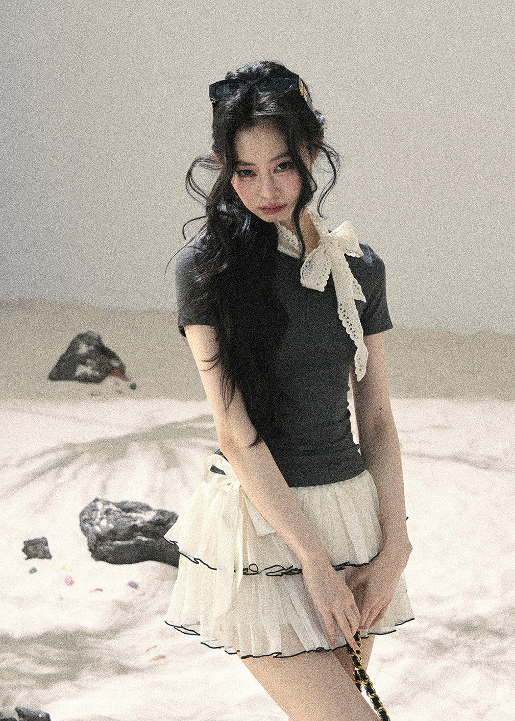 Woman wearing gray fitted T-shirt with contrast white lace ribbon bow