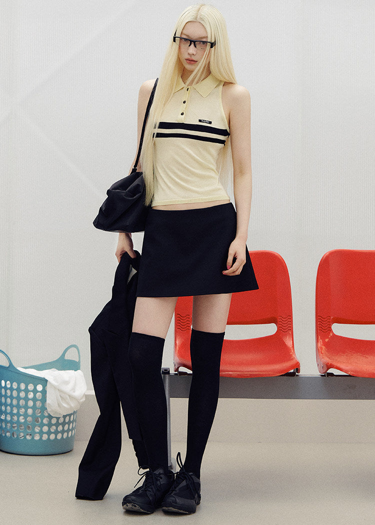 Model wearing a black A-line mini skirt with sheer knee-high socks and black shoes