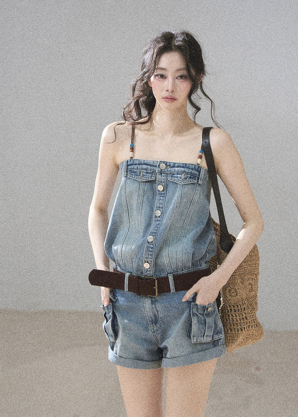 Model wearing a light wash denim romper