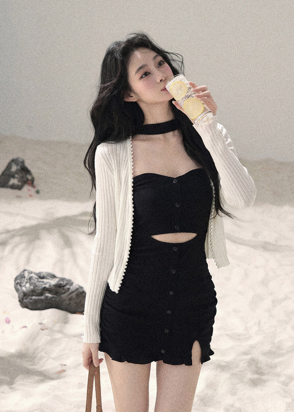 Woman wearing black halter cutout knit mini dress layered with white cardigan