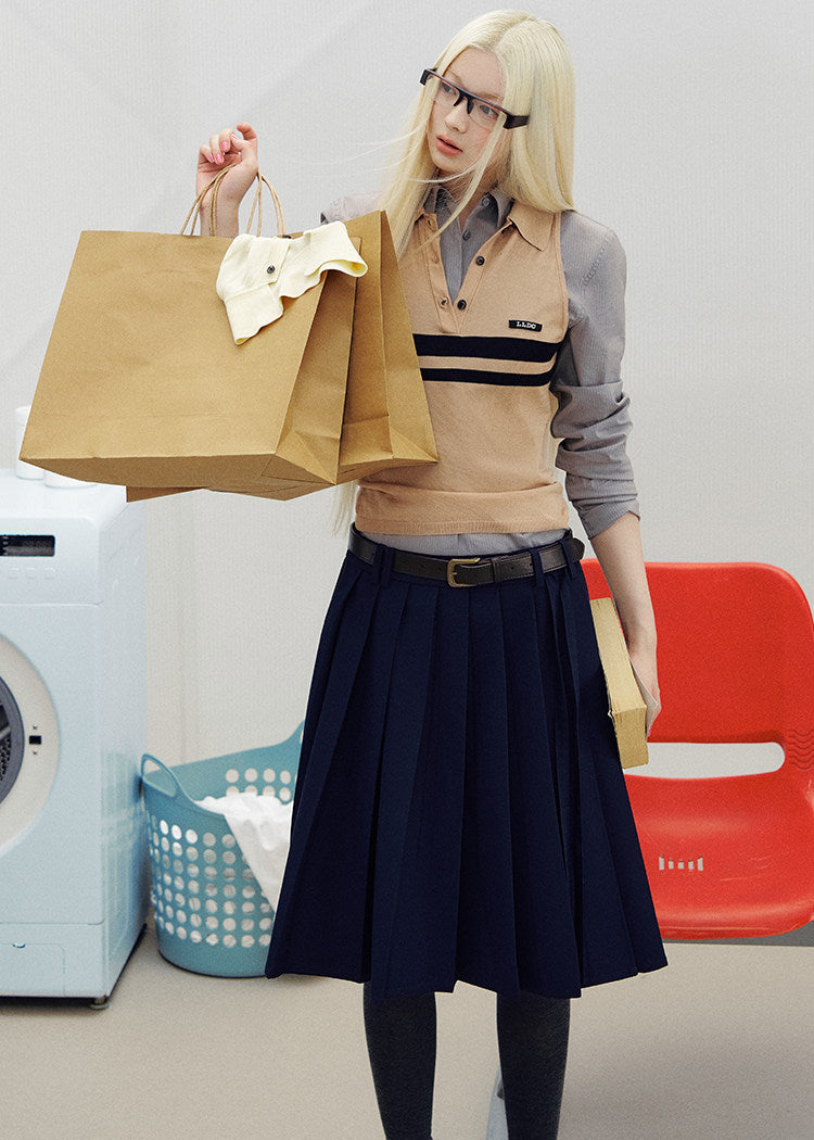 Navy pleated skirt with an asymmetric hem styled with knee-high socks and brown loafers