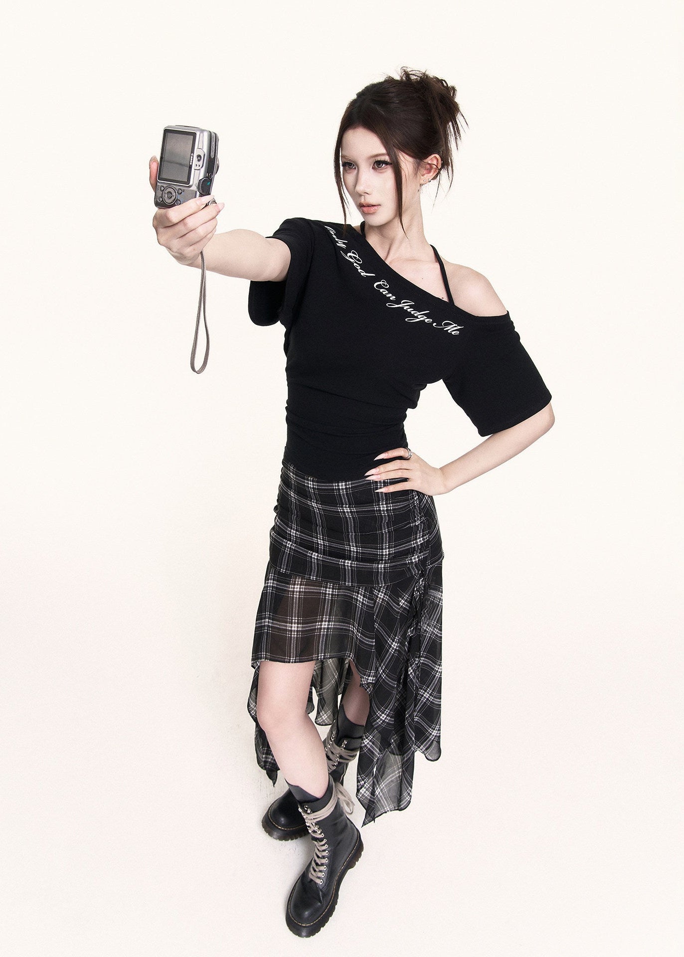 Black cross-shoulder tee styled with a plaid skirt